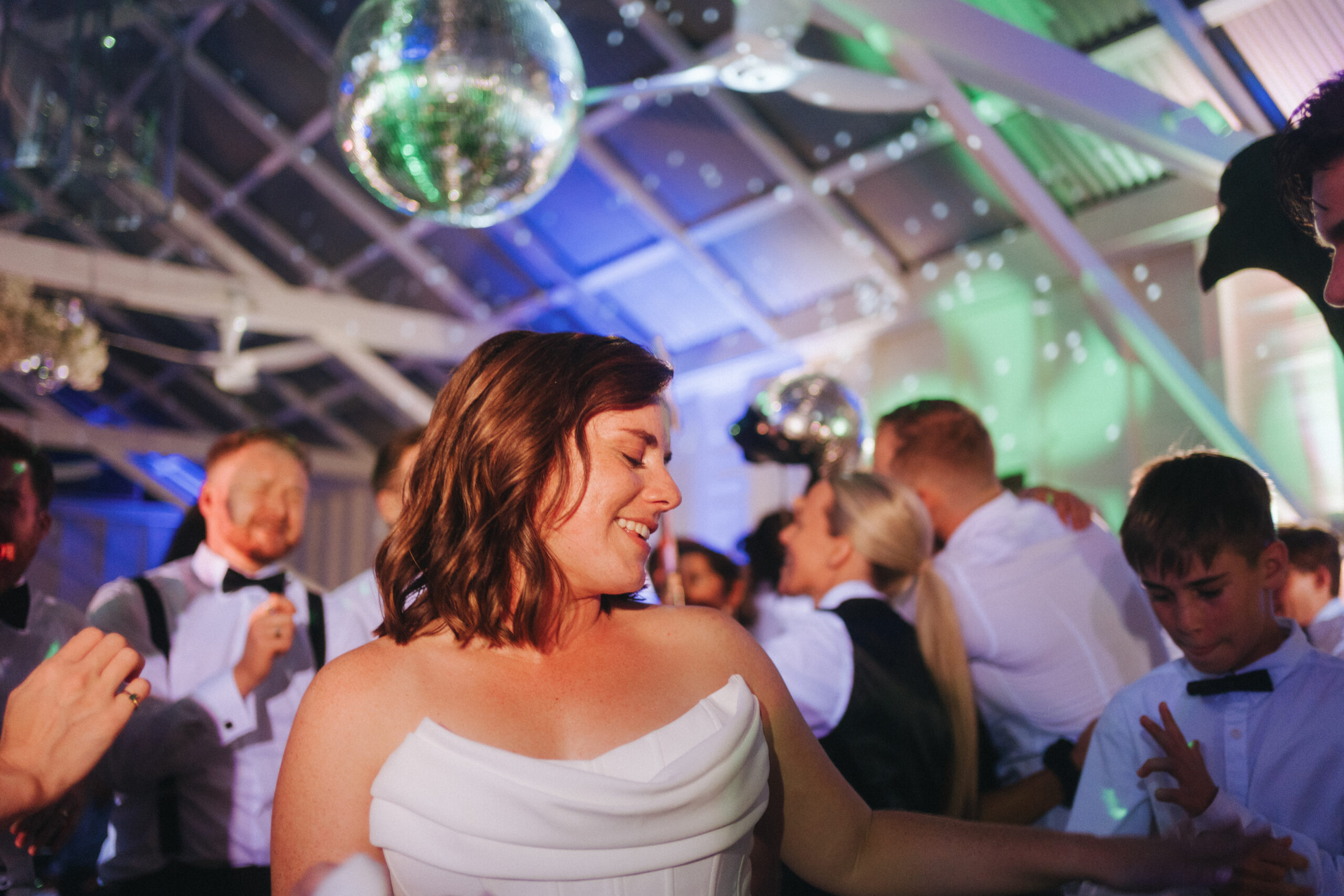 Wedding reception dance floor glowing under a canopy of disco balls, with guests celebrating beneath twinkling lights at Athol Hall